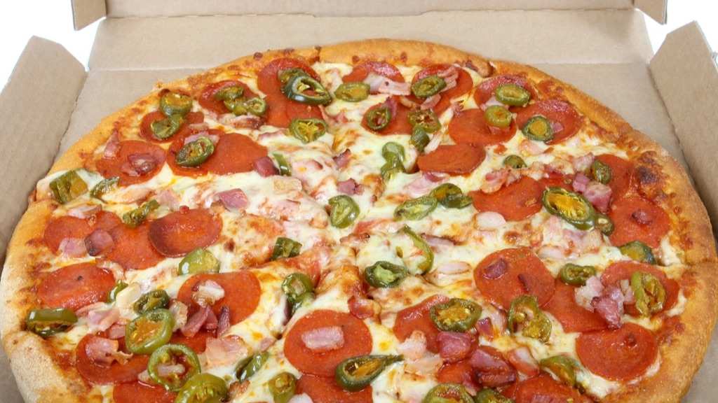 A pepperoni, bacon and jalapeño pizza in an open cardboard delivery box